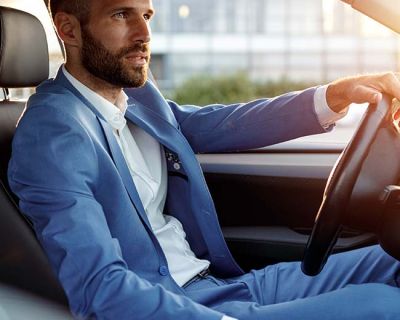 Hombre con traje azul en el interior de su vehículo