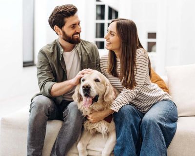 Pareja joven sentada en el sofá con su perro en el centro