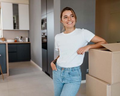 Mujer joven en una cocina apoyada en una caja de cartón