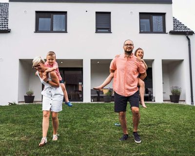 Pareja joven con niños a caballito en el jardín de su casa