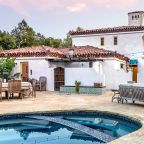 Exteriores de una villa con piscina, gran chimenea y mucha vegetación