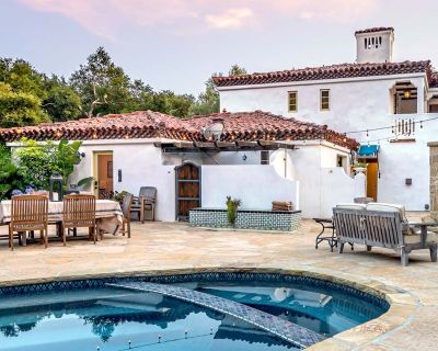 Exteriores de una villa con piscina, gran chimenea y mucha vegetación