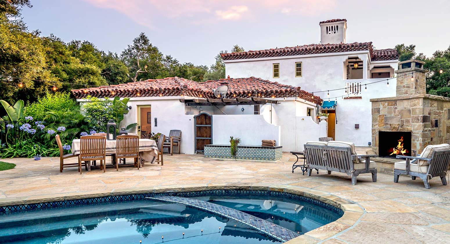 Exteriores de una villa con piscina, gran chimenea y mucha vegetación